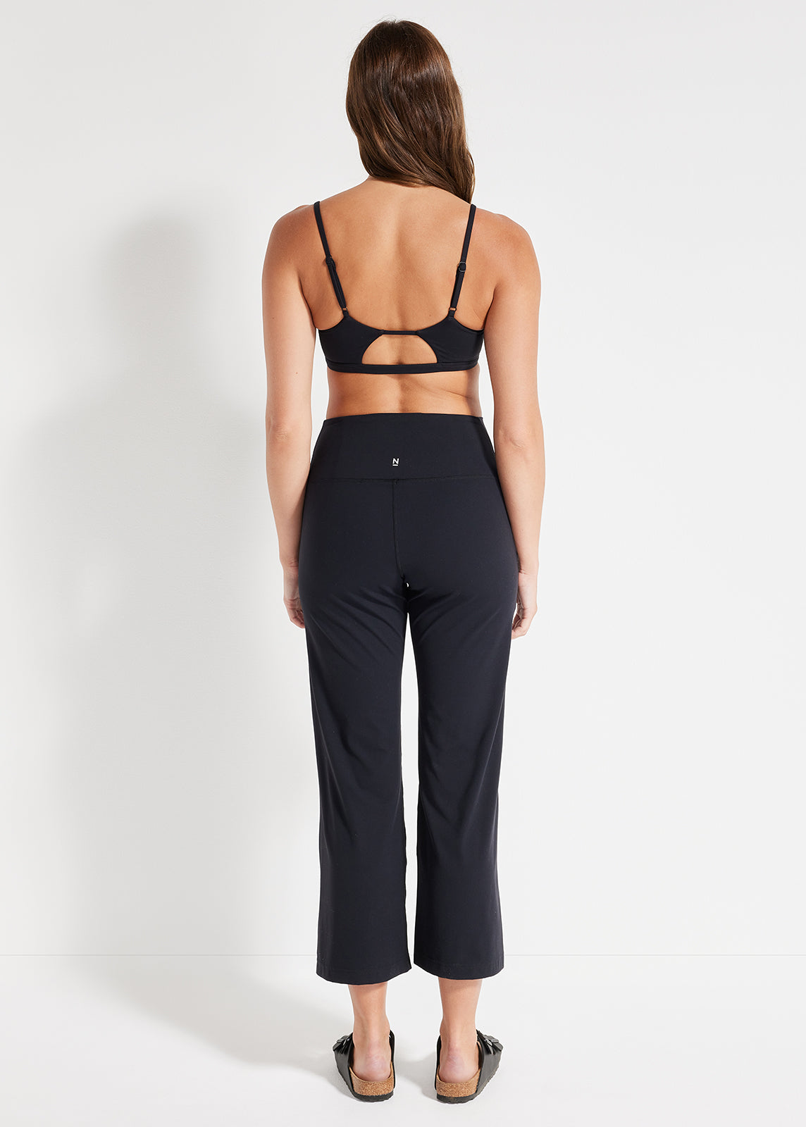 Back view of black crop and flared pants with adjustable strap detail on bra