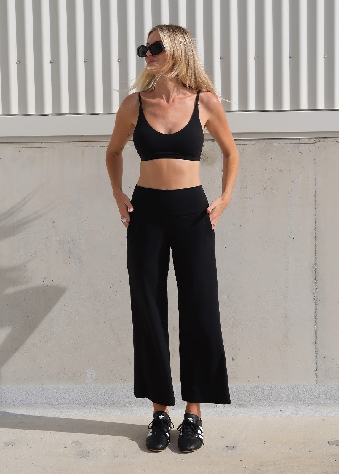 Model wearing black tights and crop top outside on a sunny day