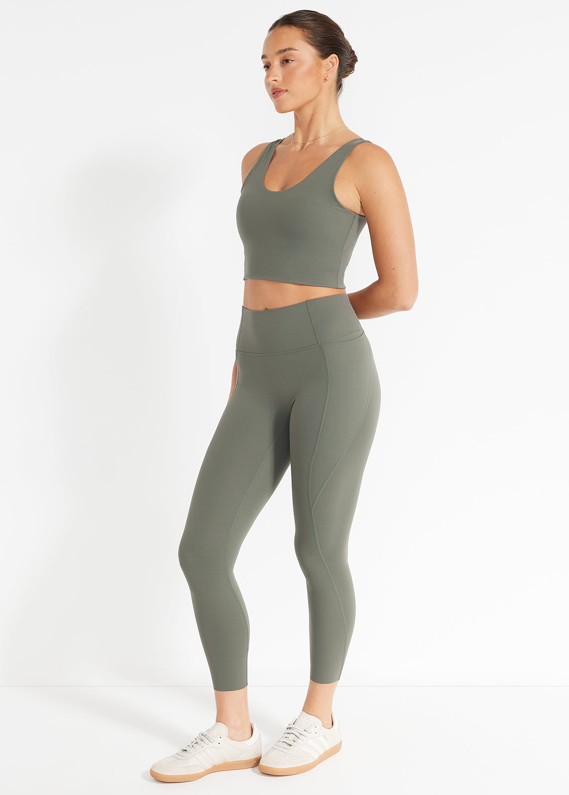 Model wearing olive green high-rise leggings and matching crop tank in studio