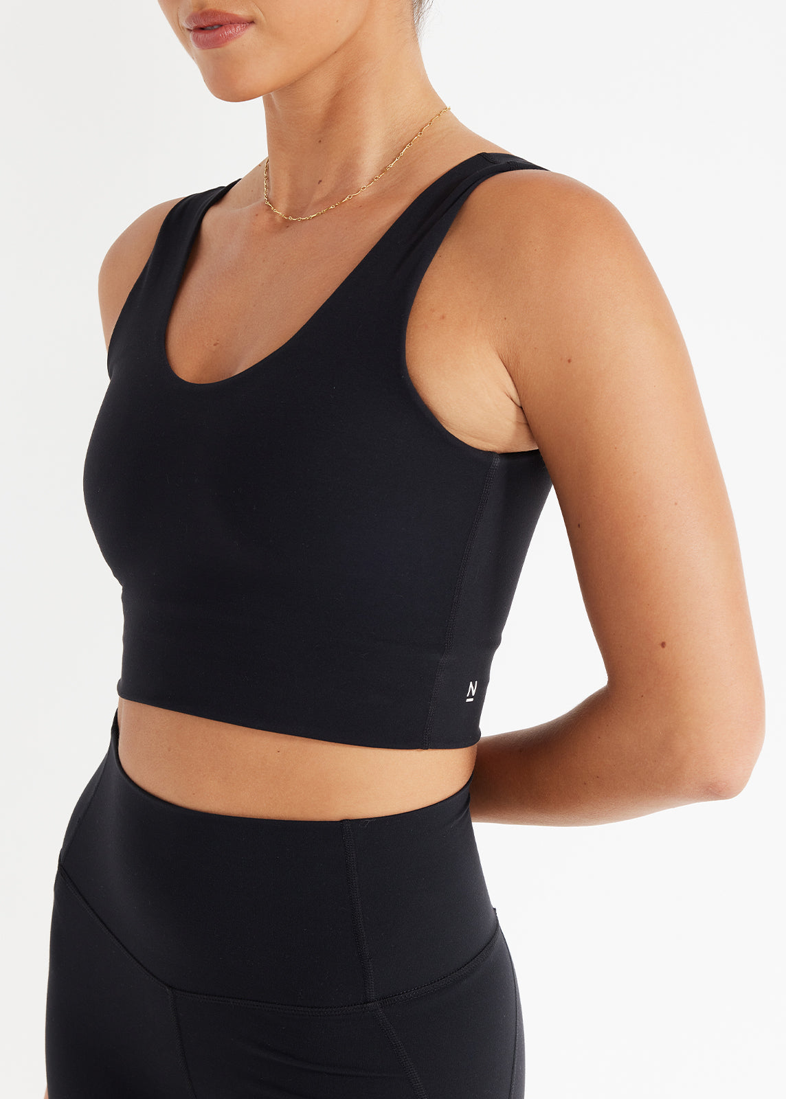 Close-up of model wearing black scoop crop tank and high-rise leggings