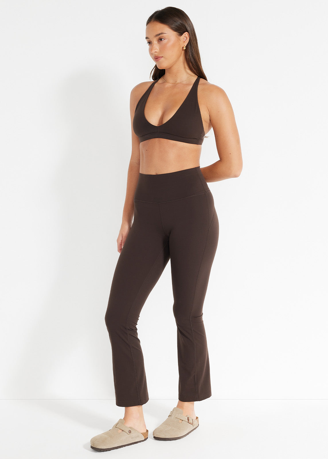 Model wearing chocolate flare leggings styled with striped shirt and slides